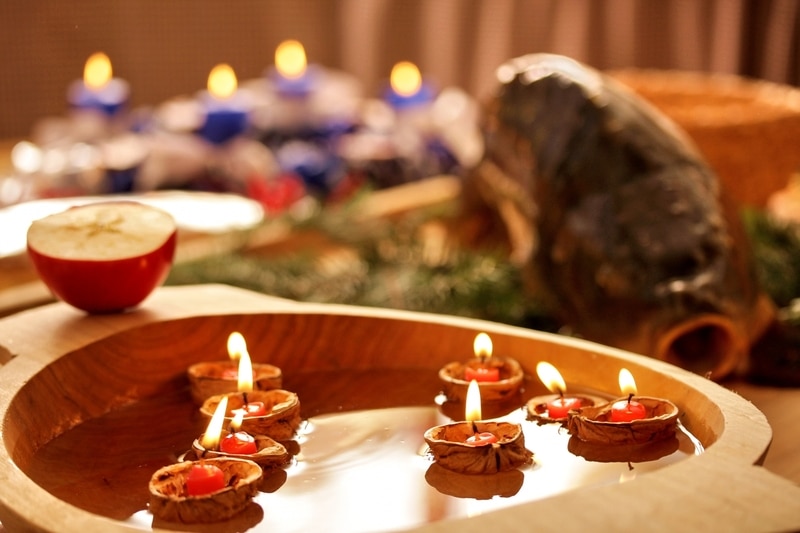 Orechové škrupiny s horiacimi sviečkami v drevenej mise naplnené vodou.