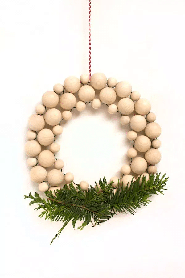 Minimalistický adventný veniec na dvere z drevených gulí v severskom štýle.