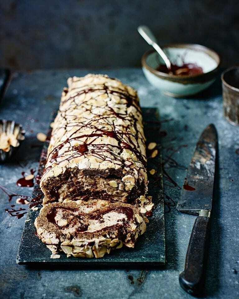 Pusinková roláda s čokoládou a kávou s vedľa položeným nožom.